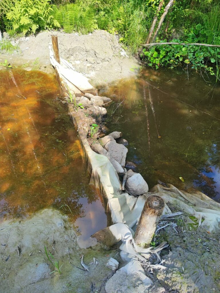 A small pond with water flowing out of it

Description automatically generated